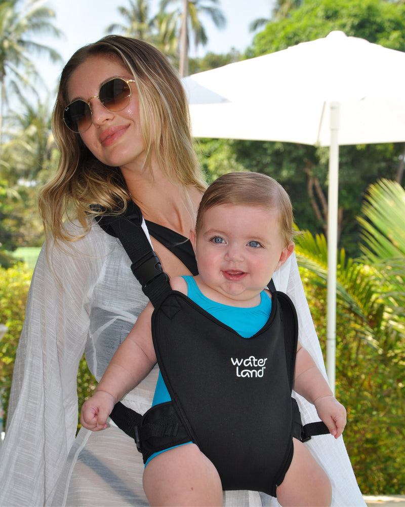 A parent standing in a resort garden, a blue-eyed baby in a Jet Black WaterLand carrier